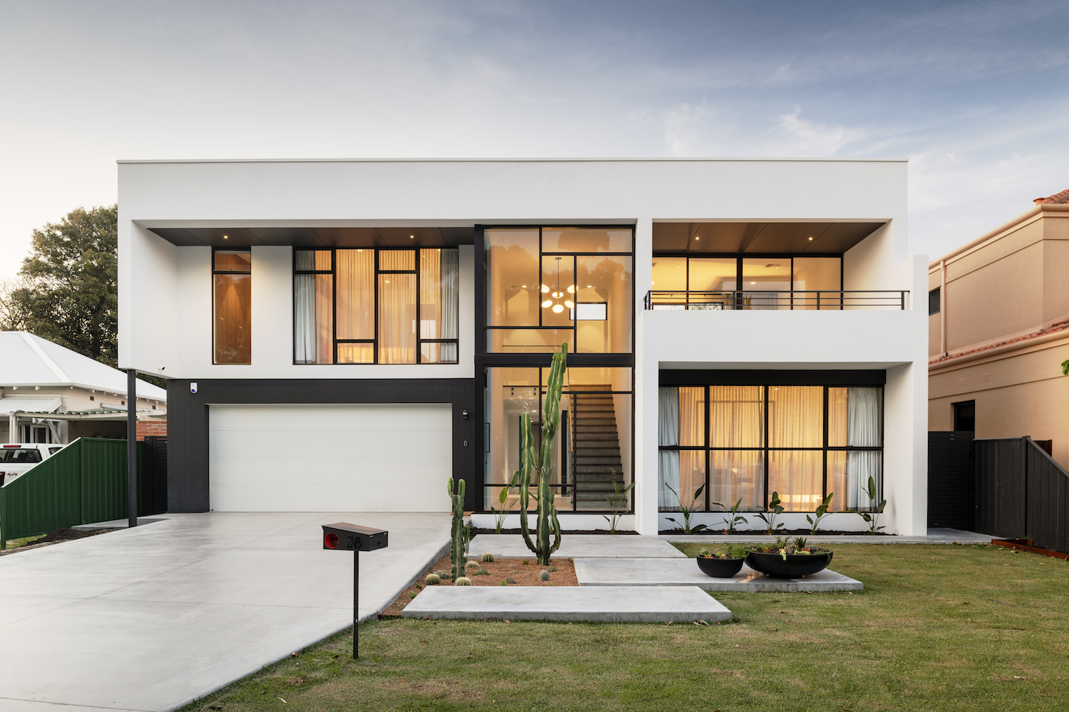 A white and modern two-story house design by Perth building company Residential Attitudes with large floor-to-ceiling windows.