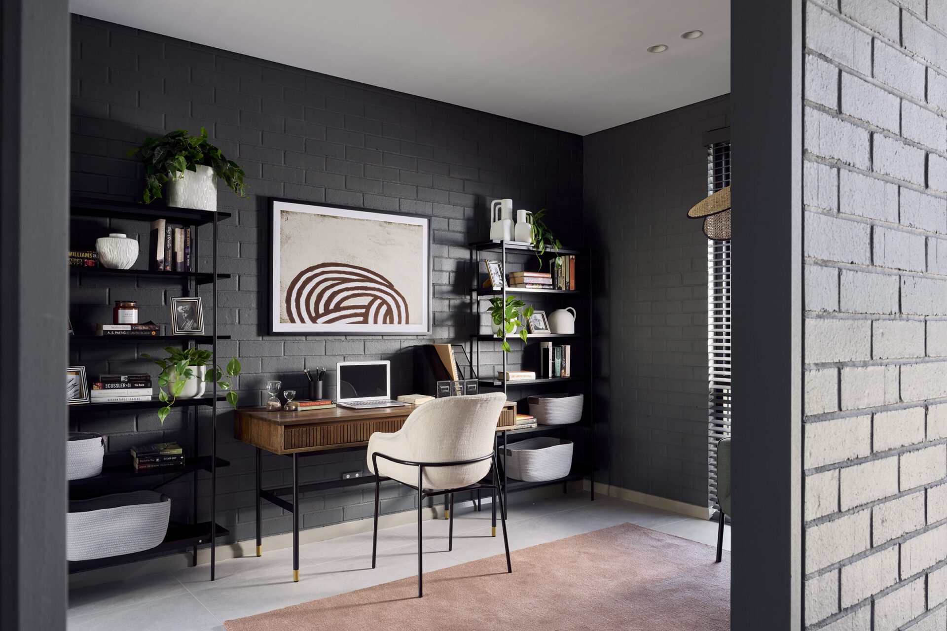 Study nook in the Double Vision display features dark brick walls drenched in natural light